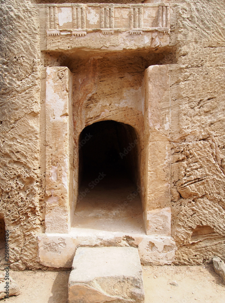 doorway carved into rock with carving and pillars at the tomb of the kings in cyprus