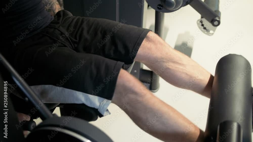 Young athlitic man does leg extensions in gym Young athlitic man does leg extensions in gym
