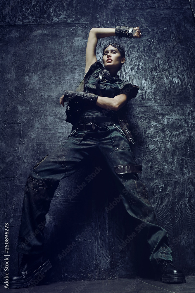 Young woman in brutal futuristic clothes on background 