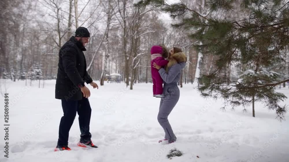 Happy young family on the street during the winter day for a walk in the Park playing with their little child