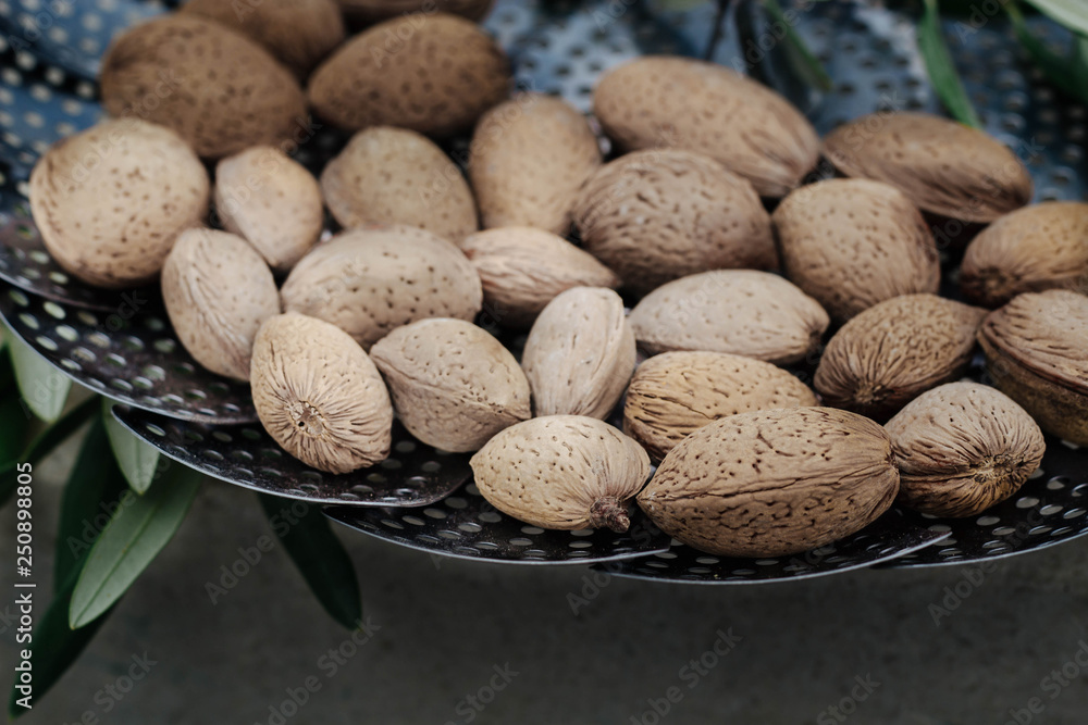 fresh, tasty almonds in shell and olive branches with olives fruits on a tray fresh, tasty almonds in shell and olive branches with olives fruits on a tray