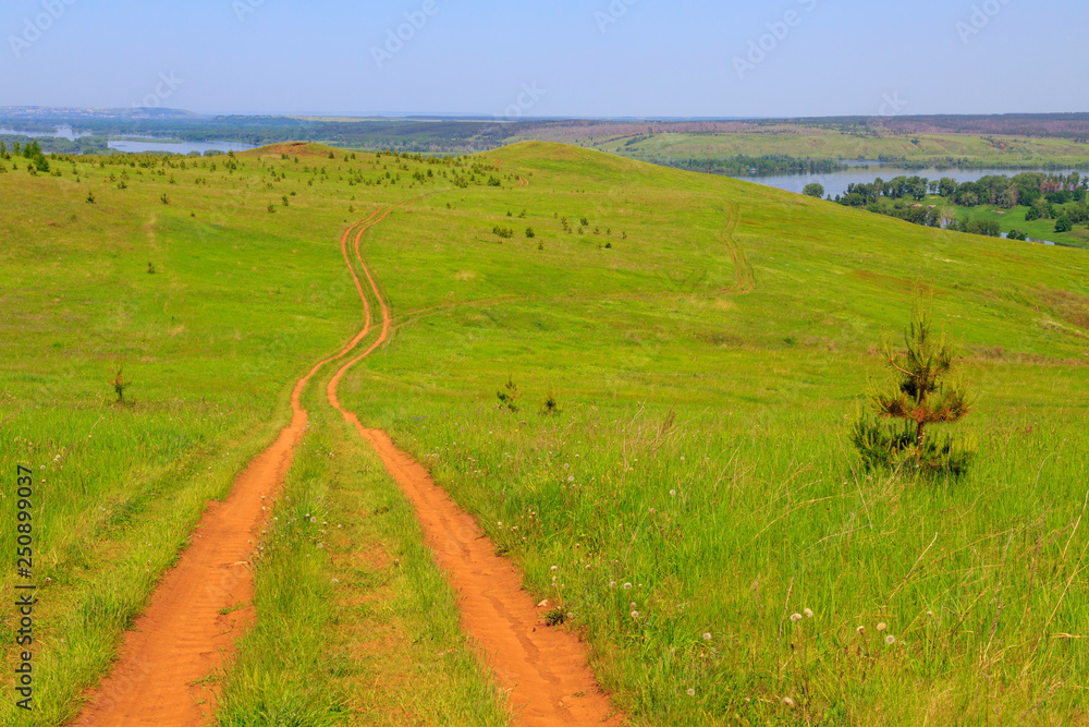 dirt road in a field along the high bank of the river Kama, summer