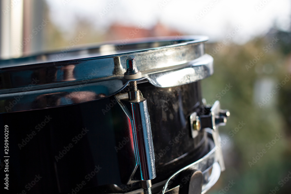 The drum set stands at the window and is lit by the rays of the spring sun and daylight, against a blurred background. Hobby and passion to music.
