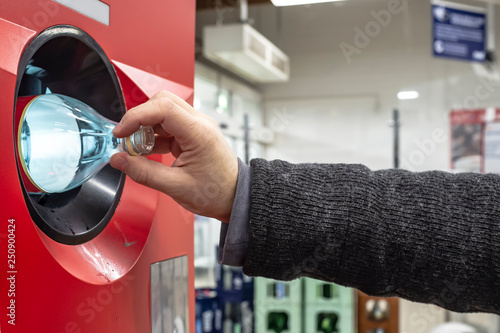 Human hand throws out a used plastic bottle in a recycling vending machine. Ecology concept.