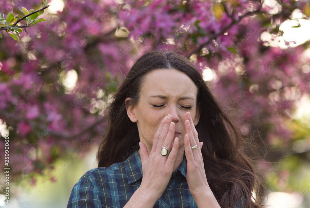 Woman sneezing because of spring pollen allergy Woman sneezing because of spring pollen allergy