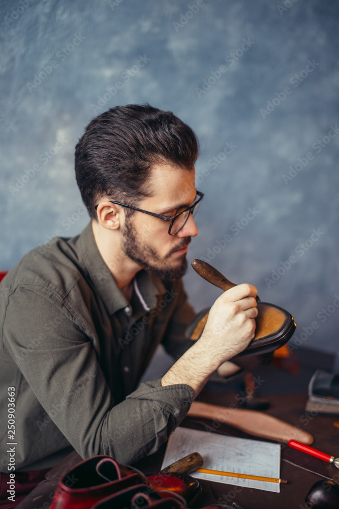 talented shoeshine man making shoes in the room with blue wall. close up side view photo talented shoeshine man making shoes in the room with blue wall. close up side view photo
