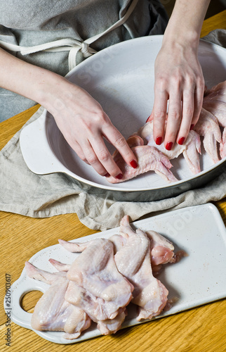 The chef puts the raw chicken wings in a baking dish. Top view