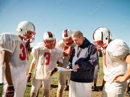 Coach instructing football players (14-15, 16-17) in field  photo