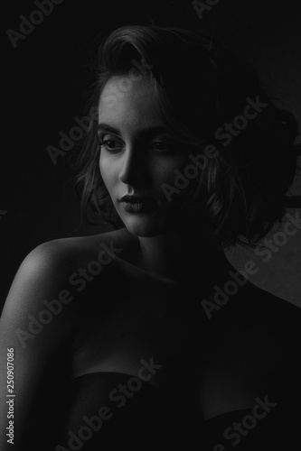 Black and white portrait of lovely brunette woman with naked shoulders