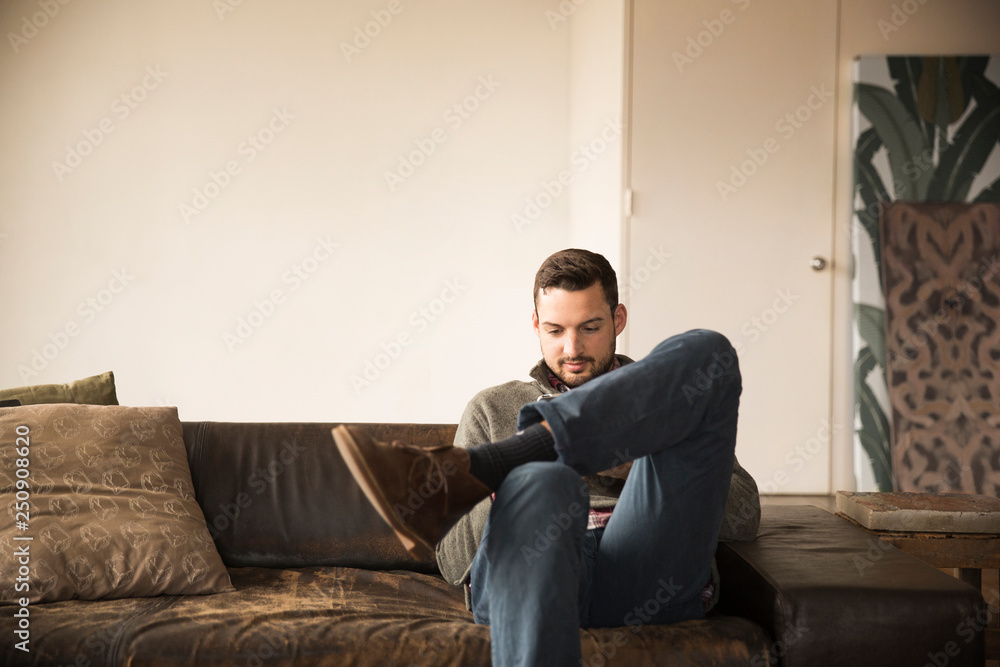 Front view of young man sitting on sofa Front view of young man sitting on sofa