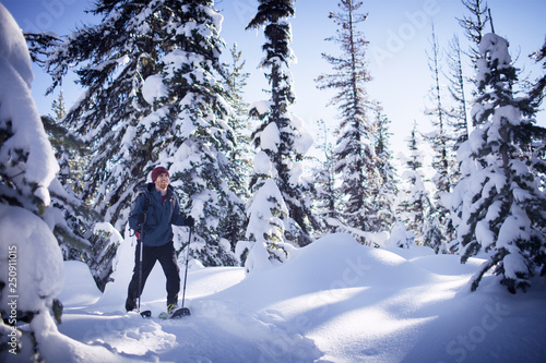 Young man snowshoeing through forest  photo