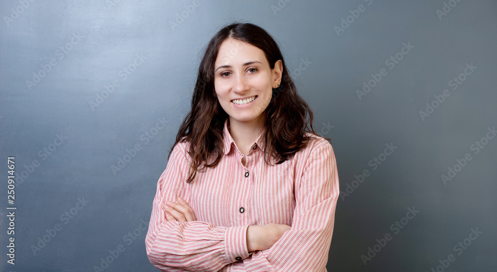 Smiling beautiful woman portrait with crossed arms on gray background Smiling beautiful woman portrait with crossed arms on gray background
