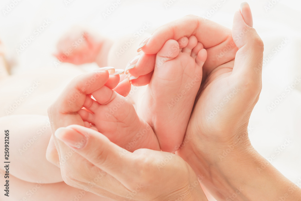 Hands of woman and baby feet, soft focus background Hands of woman and baby feet, soft focus background