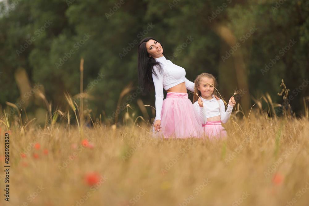 A young mother with her daughter having fun and posing in wheat fields
