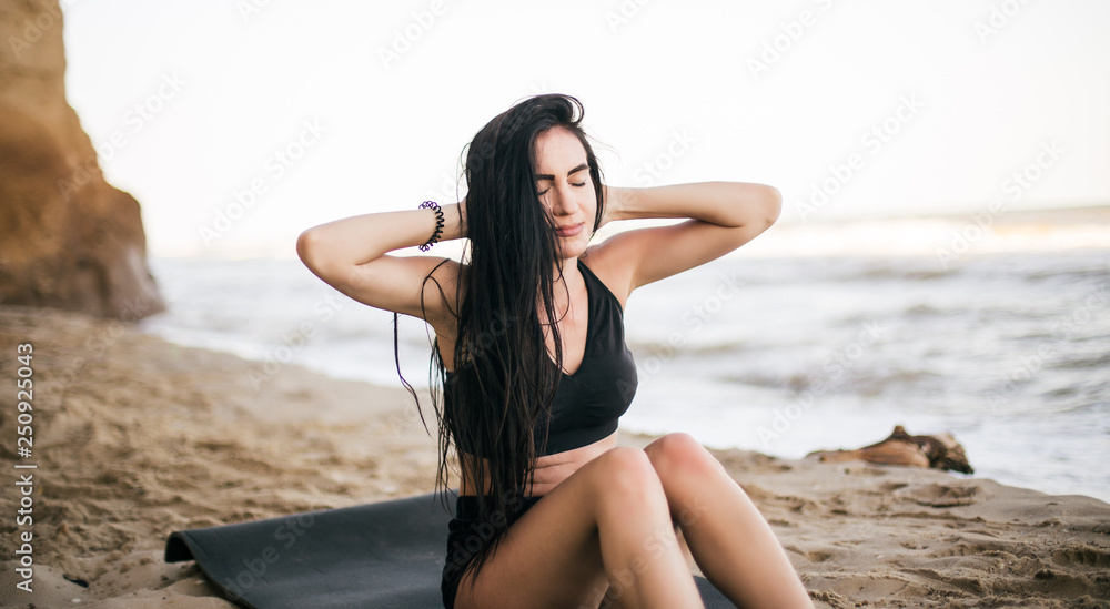 sport and lifestyle concept - woman doing sports by sea. Beautiful teenage sport woman doing stretching exercise on sand beach