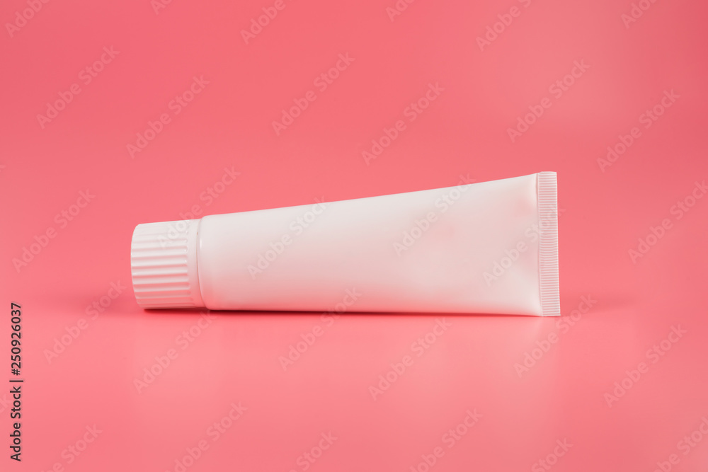 Blank white tube of toothpaste, cream or gel laying on pink background. Branding mockup Blank white tube of toothpaste, cream or gel laying on pink background. Branding mockup