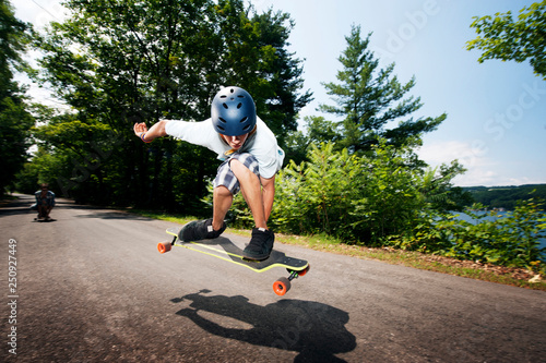 Teenage boy (14-15) jumping on longboard 