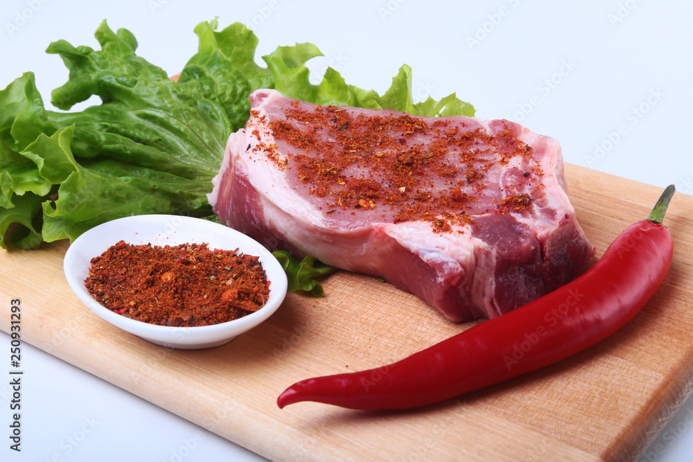 Obraz premium Raw pork steak with herbs, chili pepper and spices on cutting board. Ready for bbq.