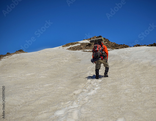 hombre adulto con mochila camina por la nieve hacia la cima de una montaña