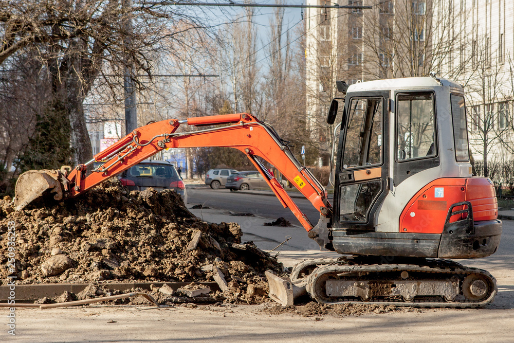 Repair of city communications. Pipeline installation. An orange excavator dug a trench for replacement old pipes Repair of city communications. Pipeline installation. An orange excavator dug a trench for replacement old pipes
