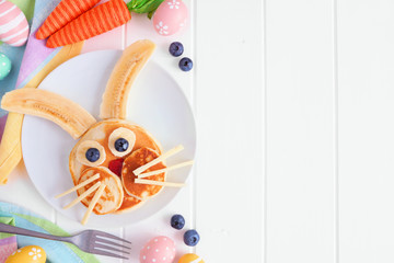 Easter Bunny breakfast pancakes on a white plate. Side border against a white wood background with copy space.