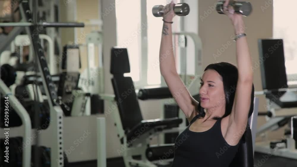 Very beautiful fitness woman exercising with dumbbells in the gym. Very beautiful fitness woman exercising with dumbbells in the gym.
