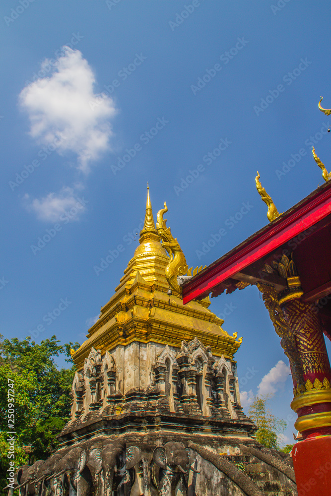 Naklejka premium Old elephant chedi with golden top pagoda at Wat Chiang Man or Wat Chiang Mun, the oldest temple in Chiang Mai, Thailand, built in 1296 by King Mengrai in Lanna-style with elephant-shaped buttresses.