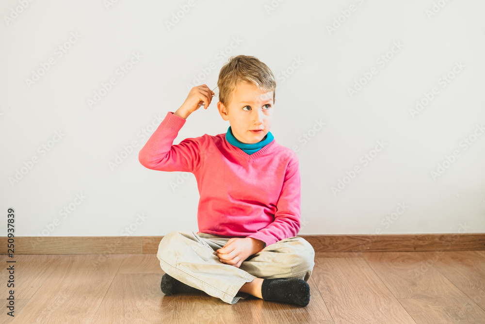 Independent child of 5 years combing himself sitting on the floor of his house - obrazy, fototapety, plakaty 