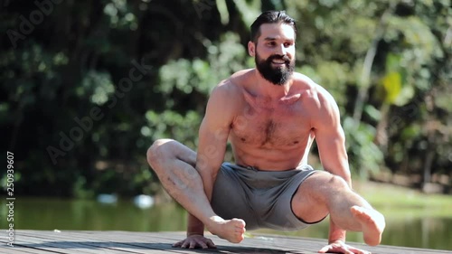 Handsome athlete exercising difficult strength Yoga pose outdoors in nature2 photo