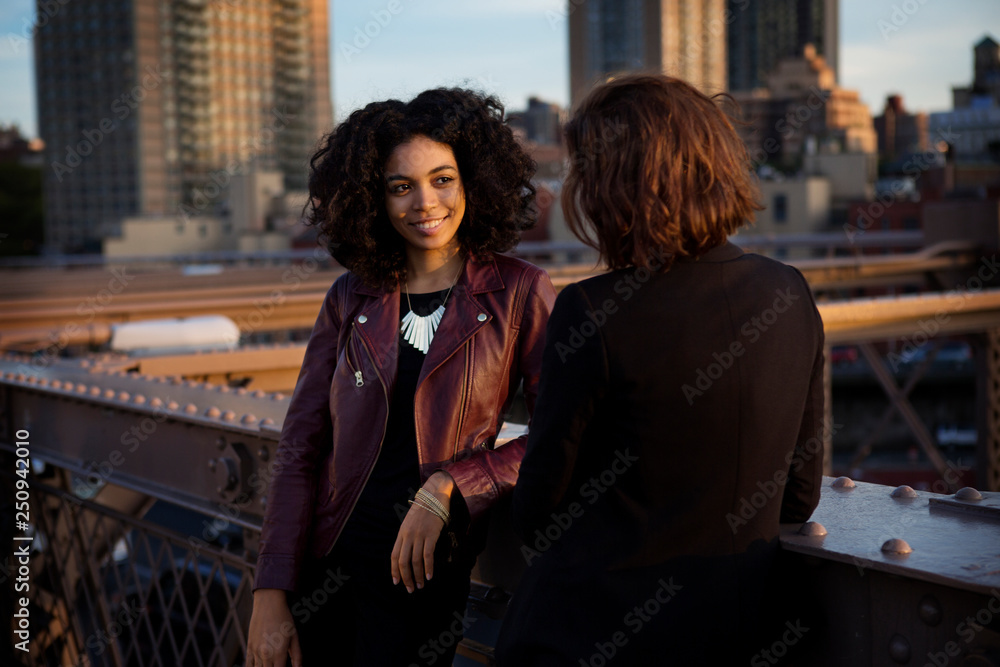 Young women talking on bridge Young women talking on bridge