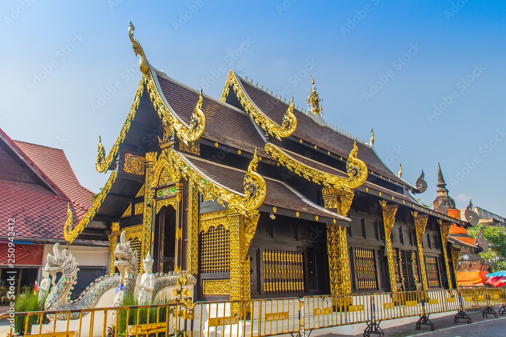 Fototapeta premium Beautiful golden Buddhist church in Lanna style architecture at Wat Inthakin Sadue Muang, Chiang Mai, Thailand. Wat Inthakin is the Buddhist temple where the Chiang Mai city pillar was placed in 1296.