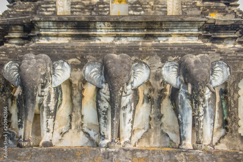 Rows of old elephant-shaped buttresses sculpture supported the chedi at Wat Chiang Man or Wat Chiang Mun, the oldest temple in Chiang Mai, Thailand, built in 1296 by King Mengrai of Lanna kingdom. photo