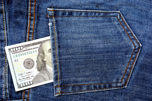 Paper banknotes of 100 us dollars in the back pocket of blue jeans. Denim backgrounds.