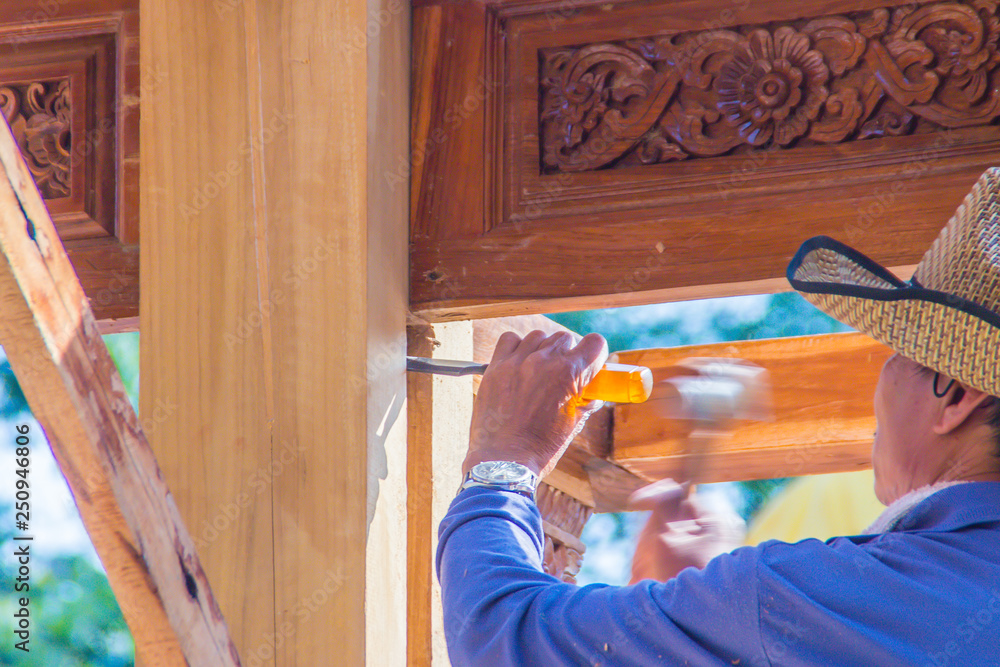 Carpenter is using chisel and hammer to groove vertical line. Close up