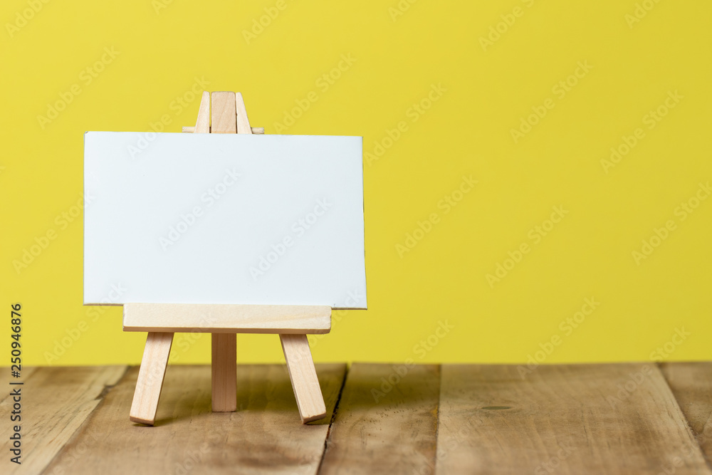 easel with blank canvas isolated on yellow background easel with blank canvas isolated on yellow background