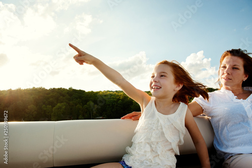 Girl (6-7) pointing on something while sitting in boat with her mother  photo