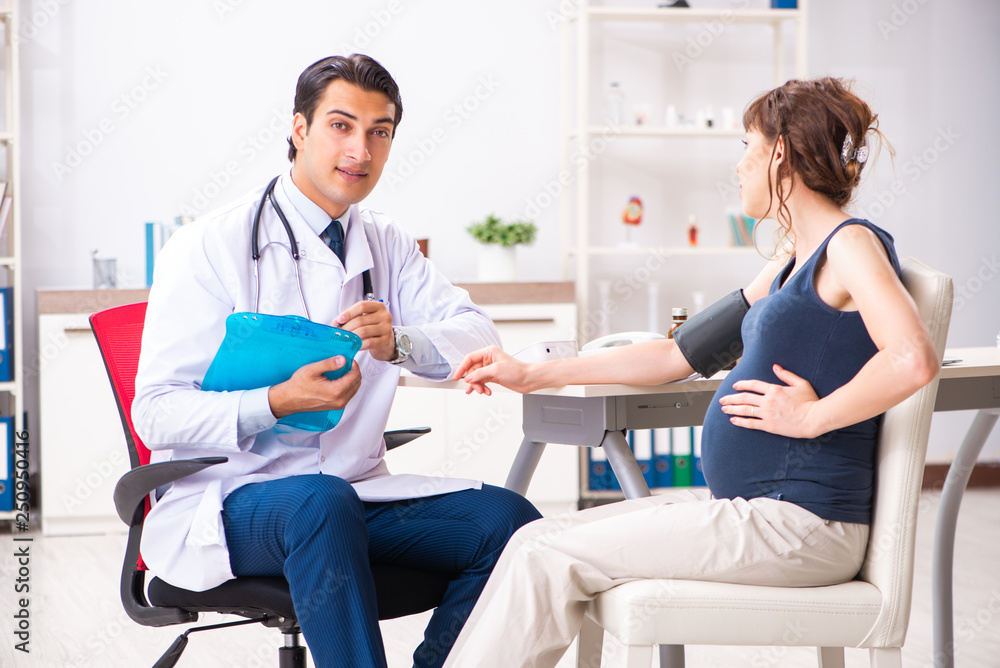 Young doctor checking pregnant woman's blood pressure Young doctor checking pregnant woman's blood pressure