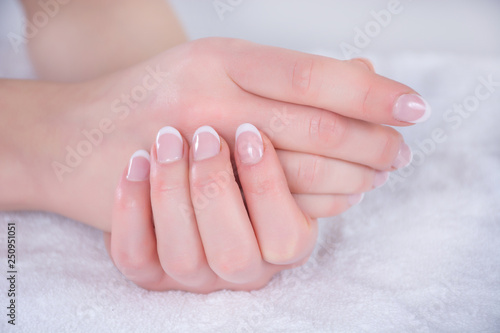Beautiful woman hands with french nails polish on white towel in beauty studio. Manicure and Beauty concept. Close up  selective focus
