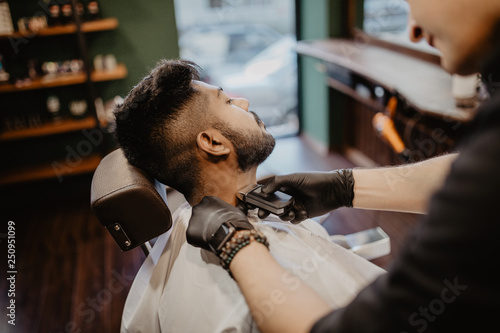 Young client during beard and moustache grooming in barber shop