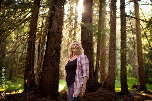 Female standing in forest sun between trees  photo