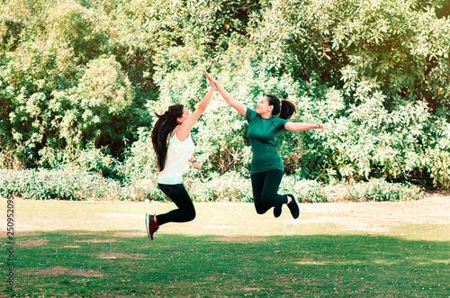 Two female friends giving high five while jumping in the air