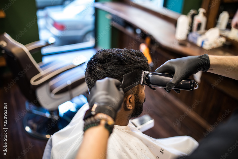 The hands of young barber making haircut with razor to attractive man in barbershop The hands of young barber making haircut with razor to attractive man in barbershop