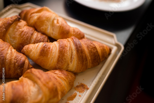 Many large croissants are placed on a light brown tray.