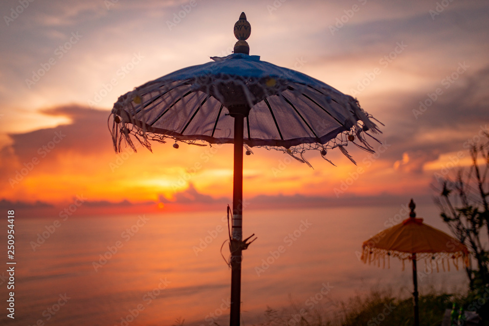 beach asian umbrella on backgrond of amazing scarlet sunset in Bali