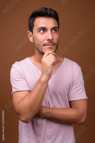 Young handsome Hispanic man against brown background