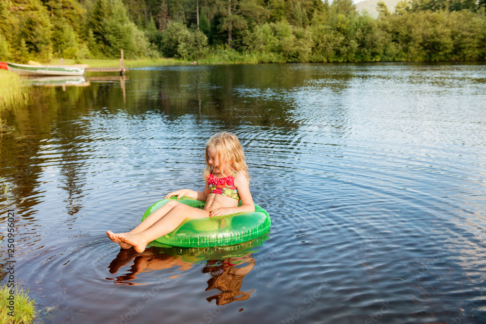 Girl (6-7) relaxing in inflatable ring on lake Girl (6-7) relaxing in inflatable ring on lake