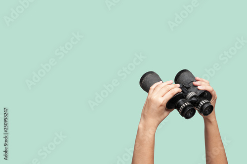 Hands holding binoculars on green background photo