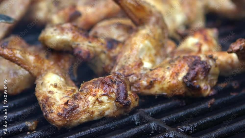 Man using metal tongs to turning some spicy chicken wings which are being grilled on a barbecue. Very delicious roast chicken meat wings that turn over on a BBQ grill. Chef cooking in backyard-Dan Man using metal tongs to turning some spicy chicken wings which are being grilled on a barbecue. Very delicious roast chicken meat wings that turn over on a BBQ grill. Chef cooking in backyard-Dan