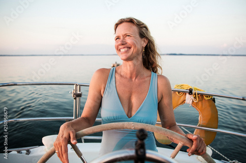 Smiling woman at helm of private yacht 