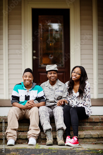 Soldier mother sitting with her children on doorstep photo